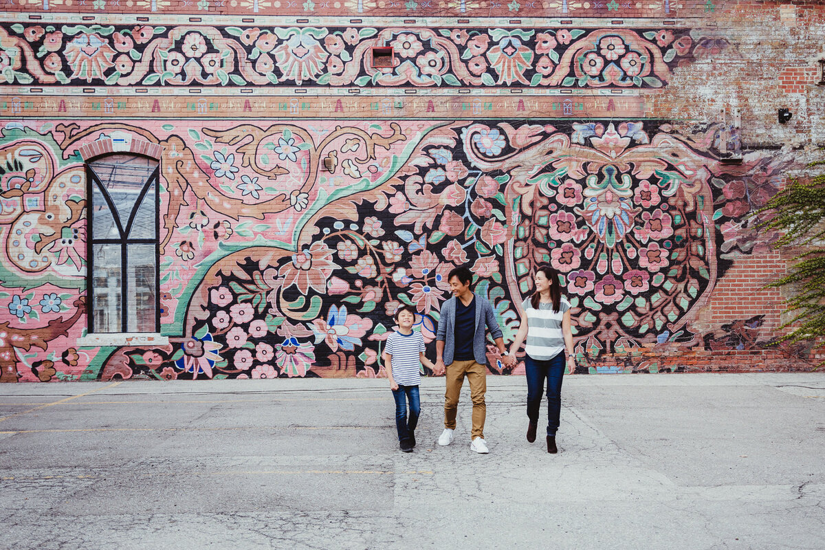 Family of 3 walking in front of colourful mural during family photo session