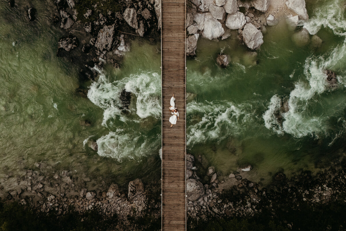 Aerial drone shot suspension bridge over turquoise water romantic couple