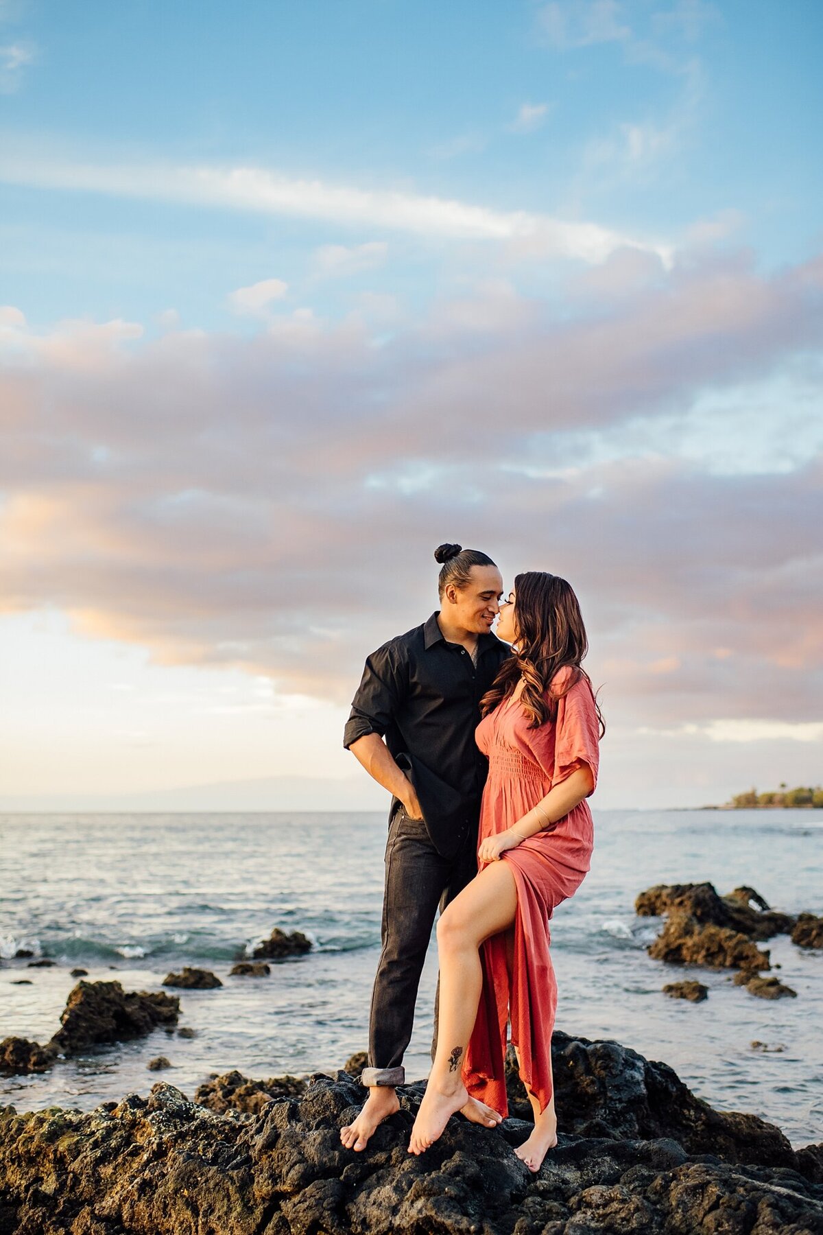 sweet couple standing on lava rocks at sunset