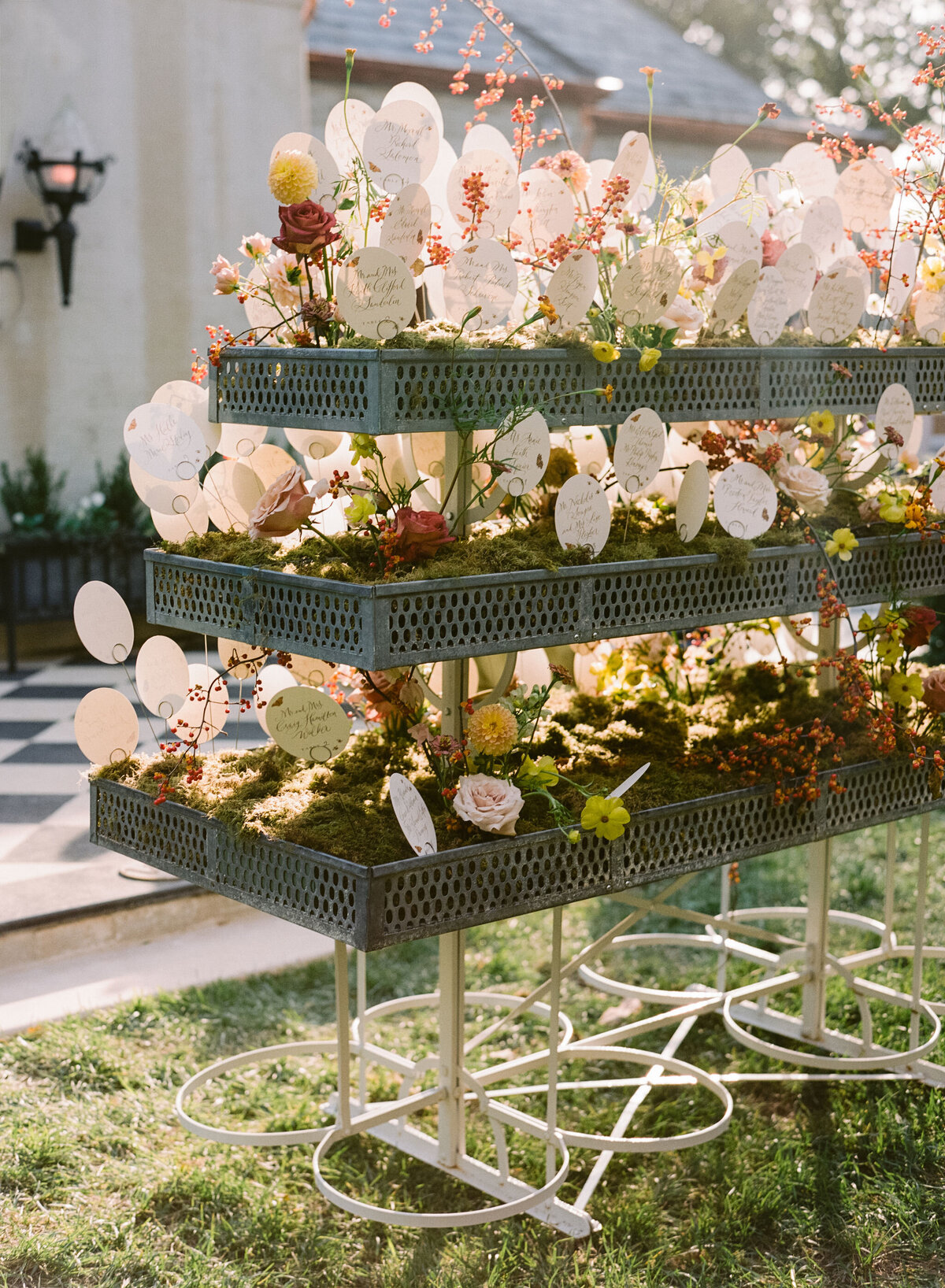 Unique floral planter escort display for fall wedding at private residence. Moss filled planters with floral such as ranunculus, butterfly ranunculus, roses, zinnias, and bittersweet popping out to create organic floral design for fall wedding reception escort display. Design by Rosemary & Finch Floral Design in Nashville, TN.