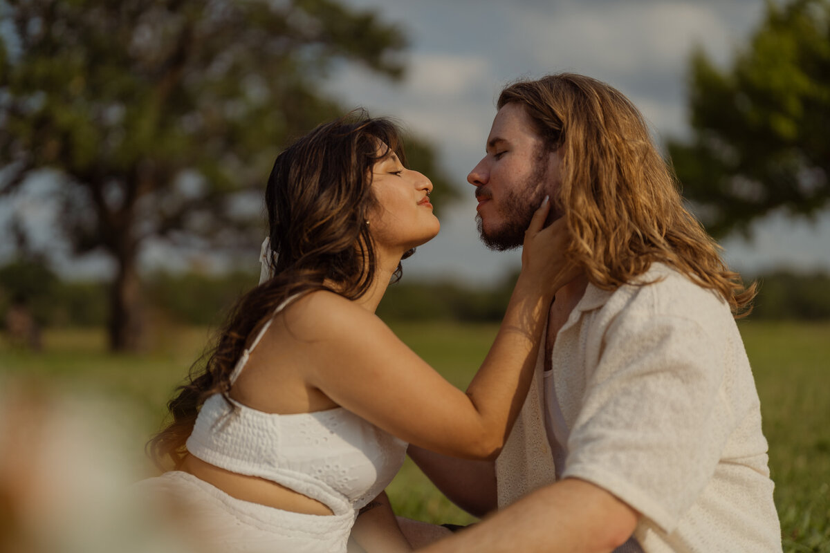 A warm photo of the couple embracing and gazing at each other lovingly, taken in the park near White Rock Lake.