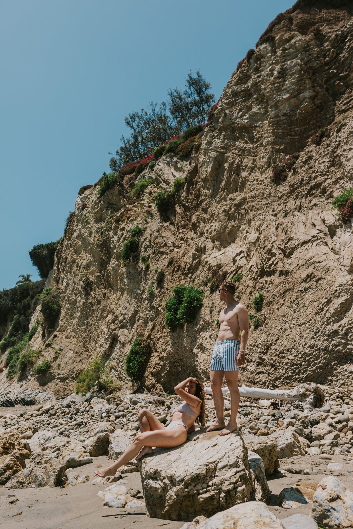 Couple standing on rocky cliff, scenic Indiana engagement photo.