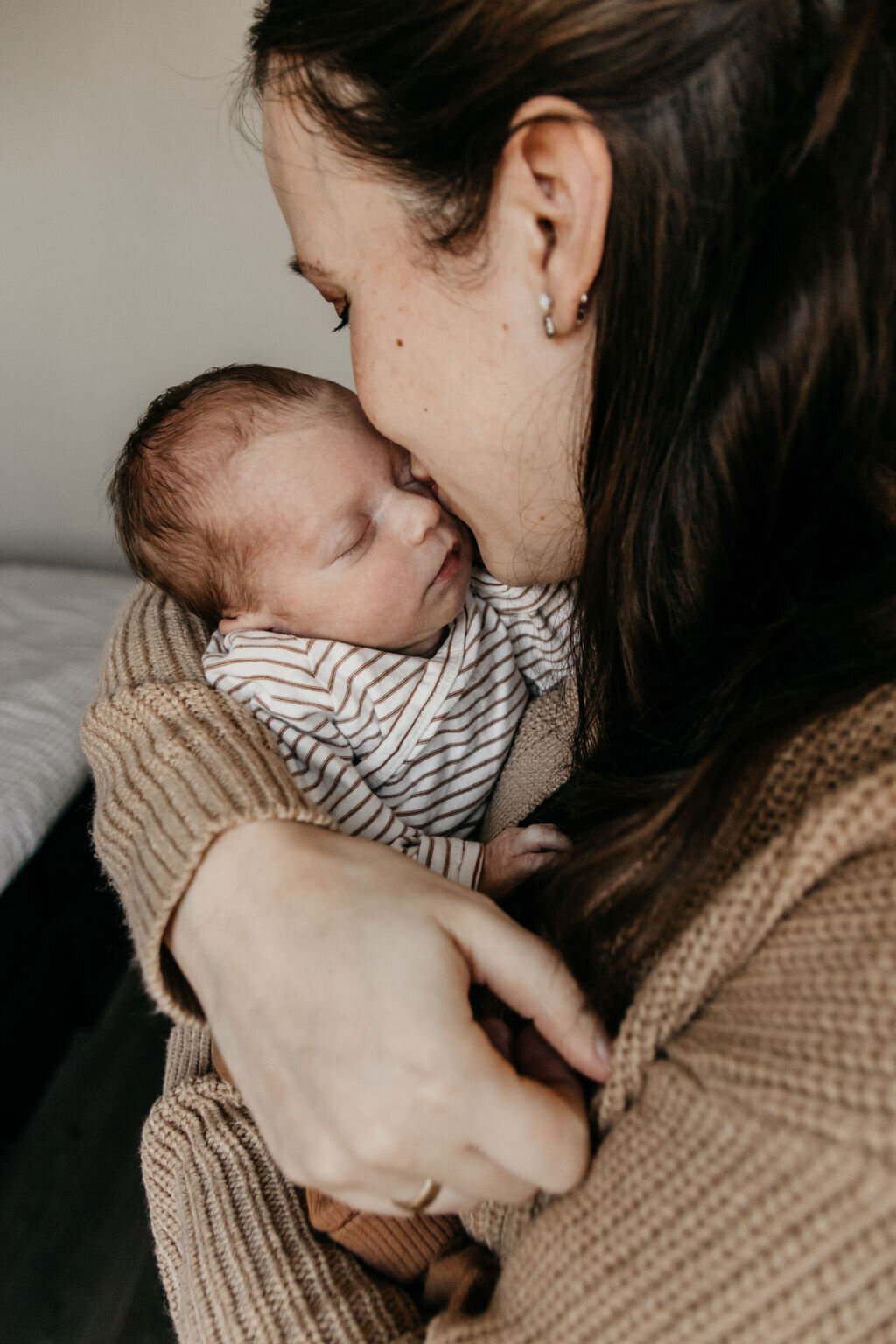 Moeder geeft newborn baby een kusje tijdens de rustige newbornshoot