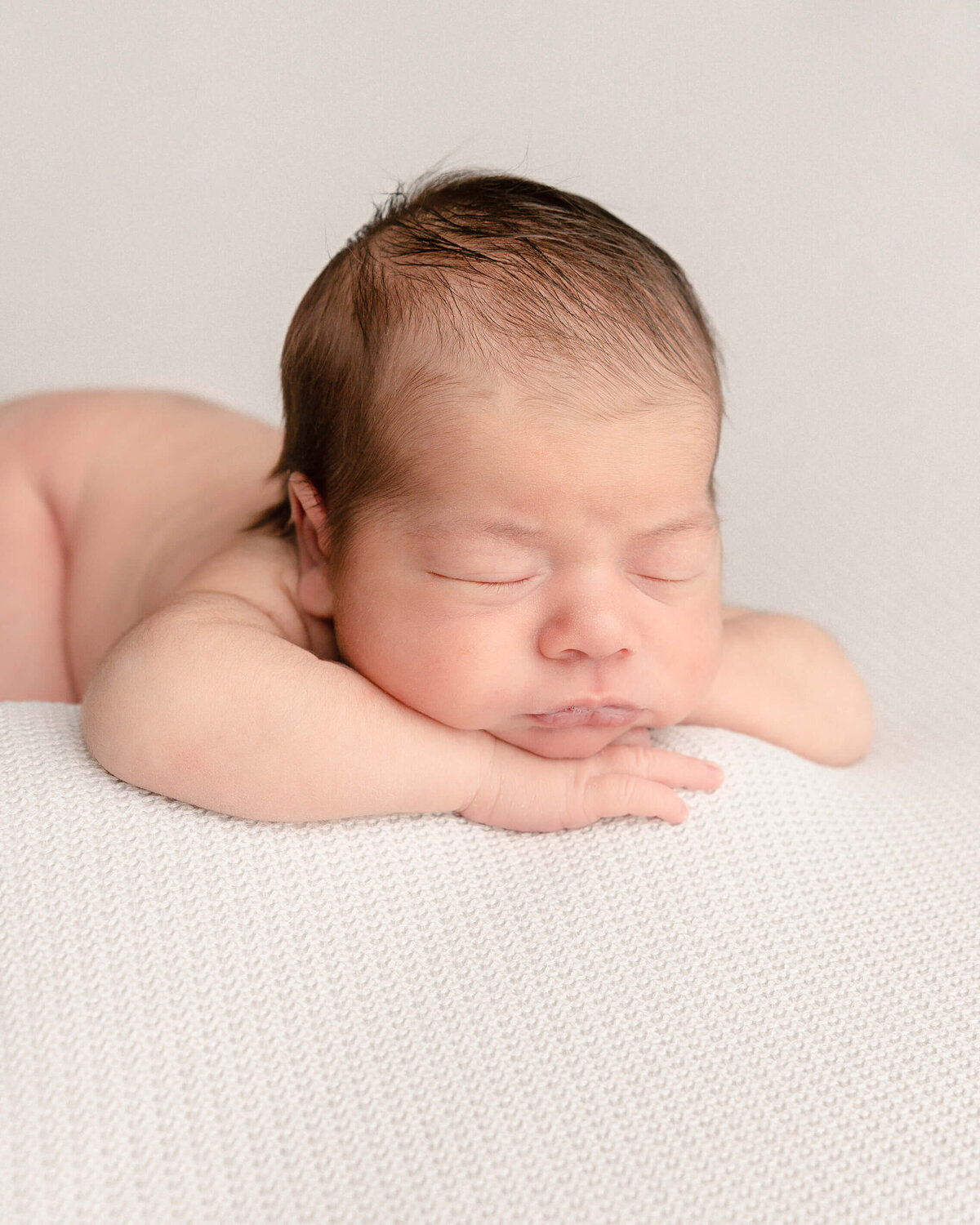 baby boy sleeping with head on hands on white blanket in portland oregon photography studio