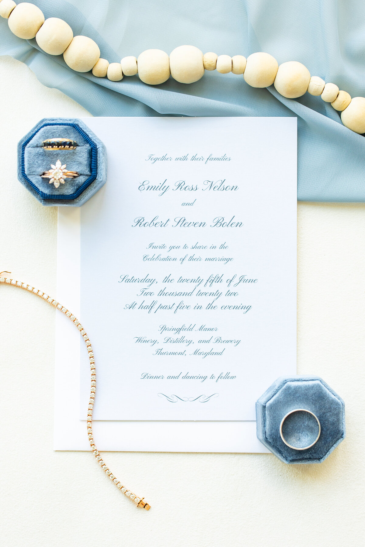 Wedding invitation next to bride and grooms rings