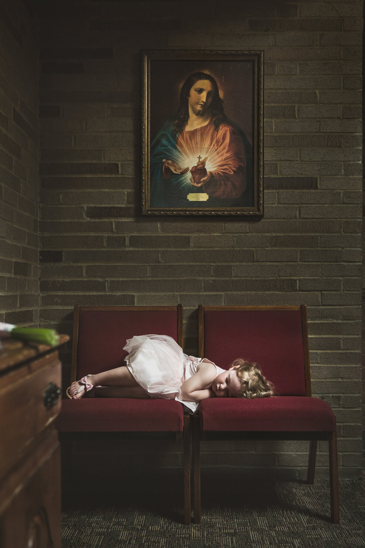 Wedding flower girl falling asleep at church.