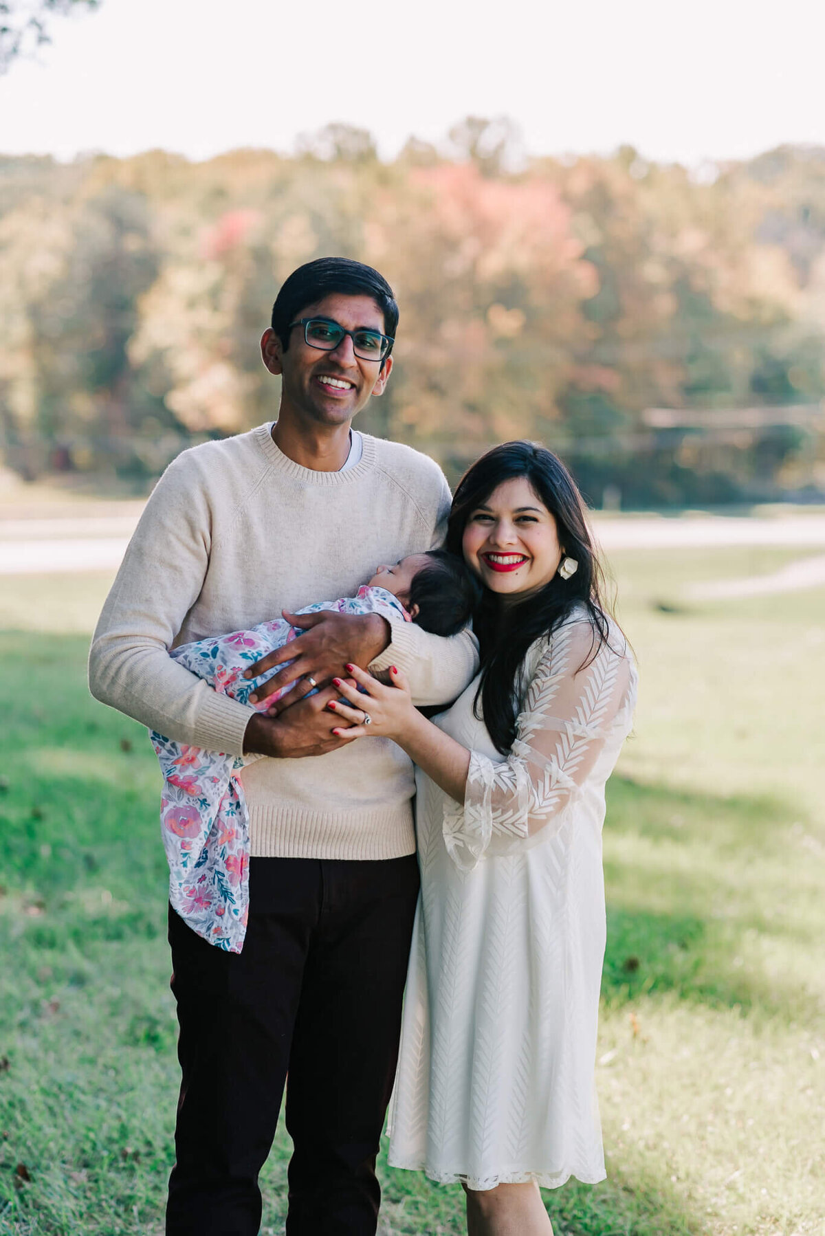 outdoor portrait of indian parents holding their sleeping baby girl during their newborn session