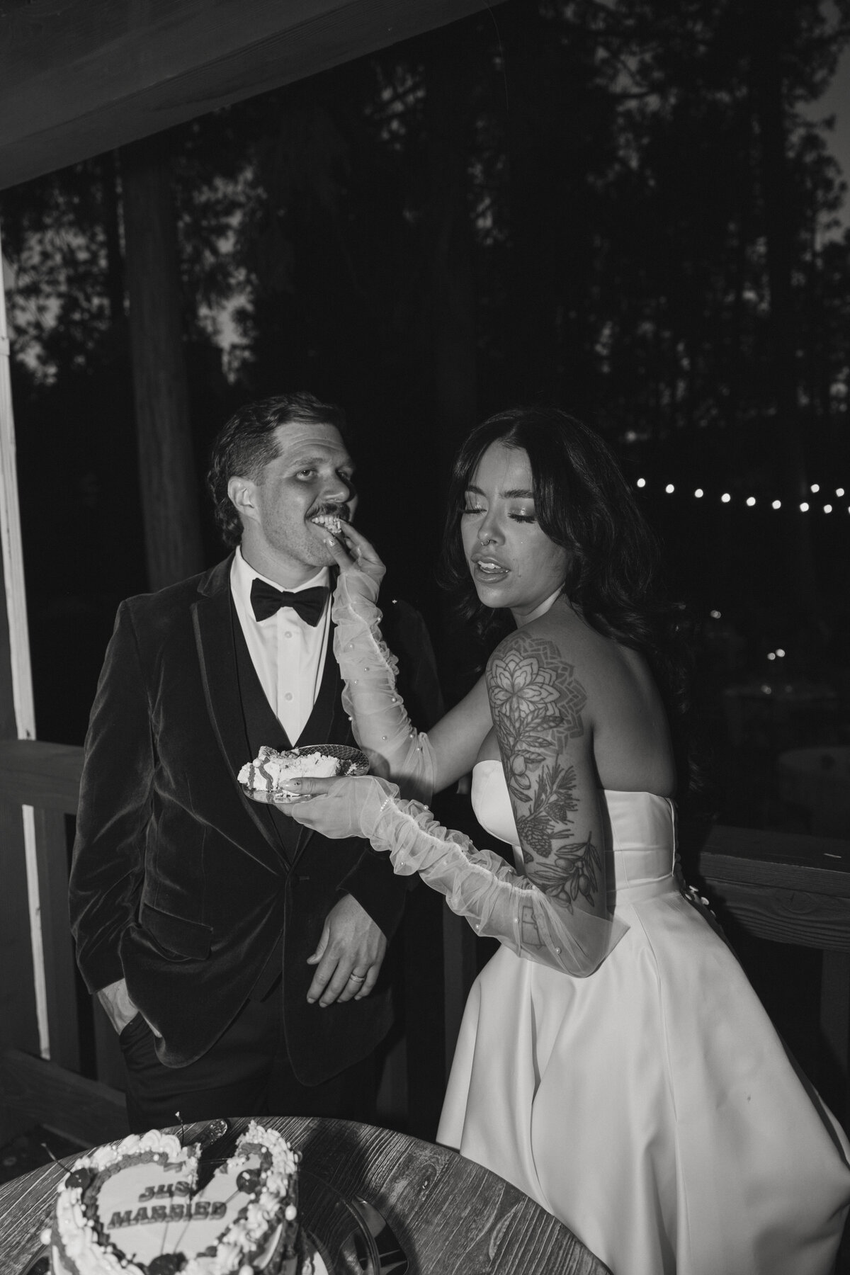 bride and groom in black and whiten feeing each other cake