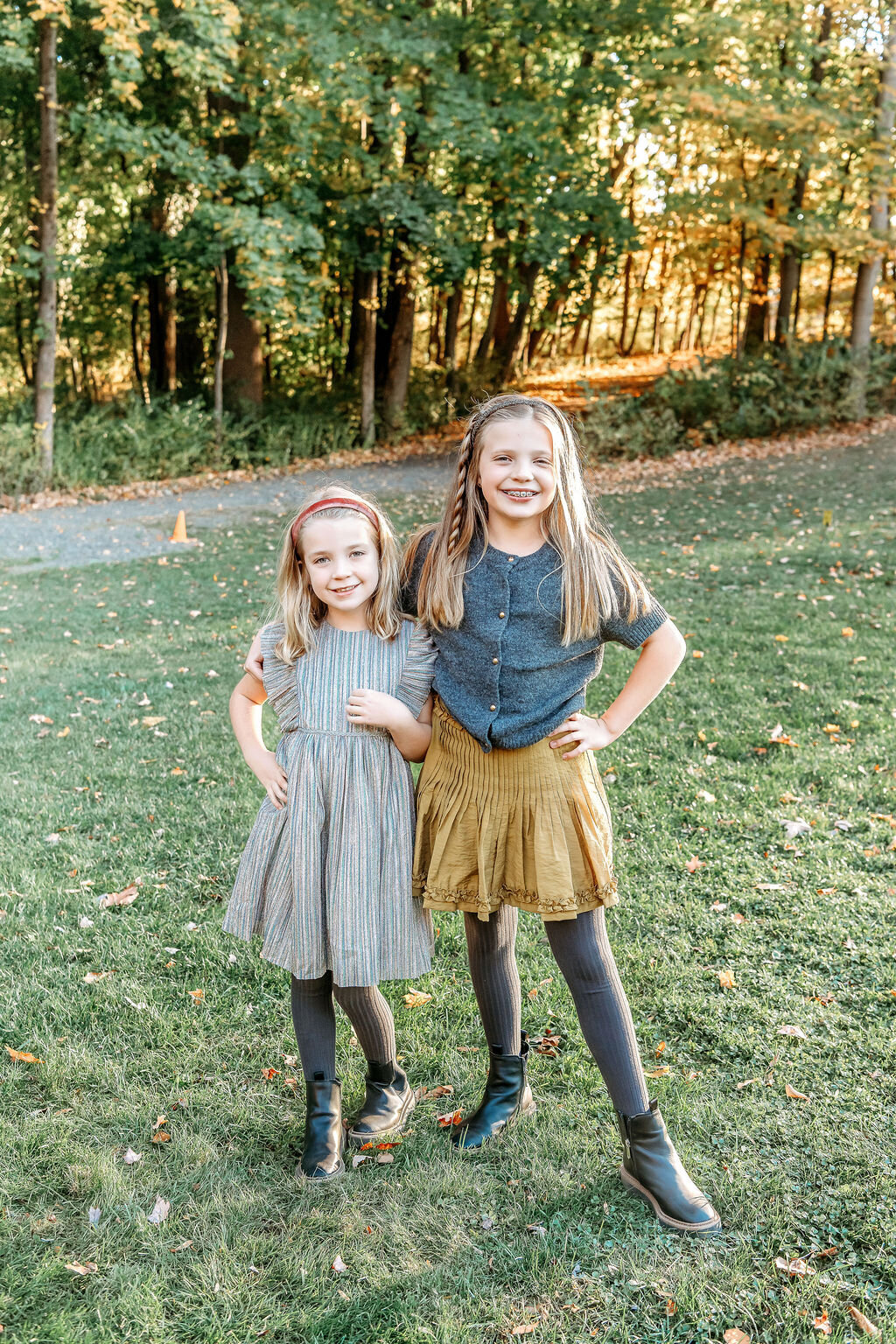 Two sisters in coordinating fall outfits posing together during Connecticut family photographer outdoor autumn session
