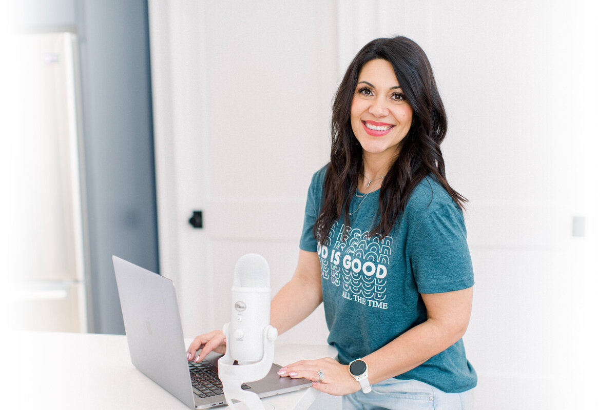 Stefanie Gass smiling with God is Good shirt white microphone and laptop
