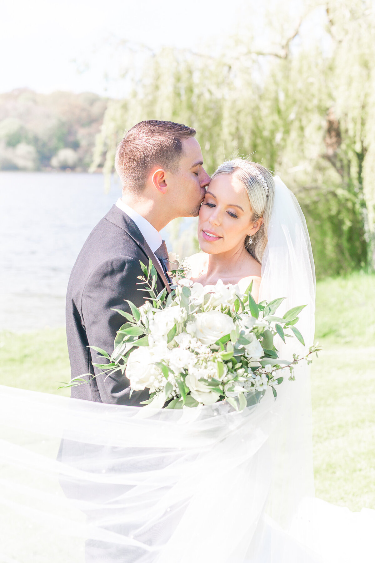 Bride and groom portrait with the veil swooping across in front of bridal bouquet