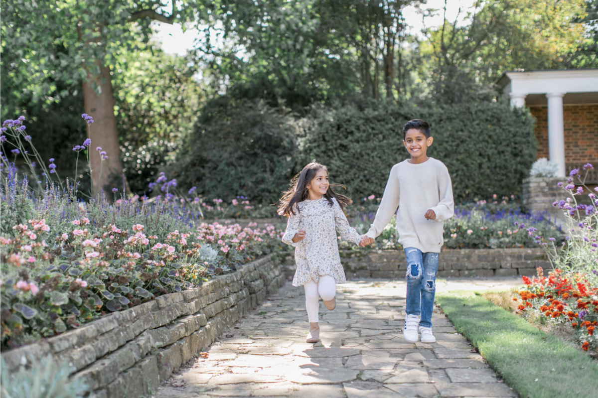 Young boy and gil holding hands skipping and smiling at their London Family Mini Shoot with Philippa Sian Photography
