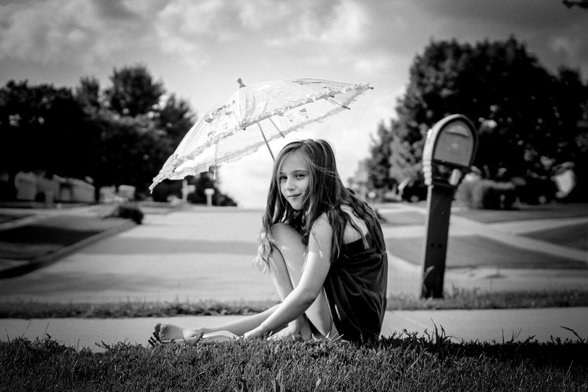 girl with long hair sitting under umbrella in summer