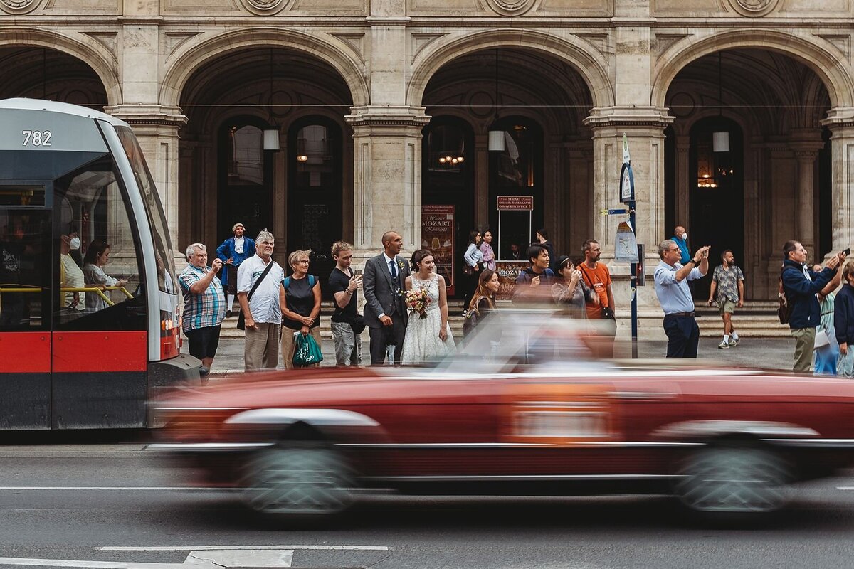 blurring image of car driving past wedding couple on steps