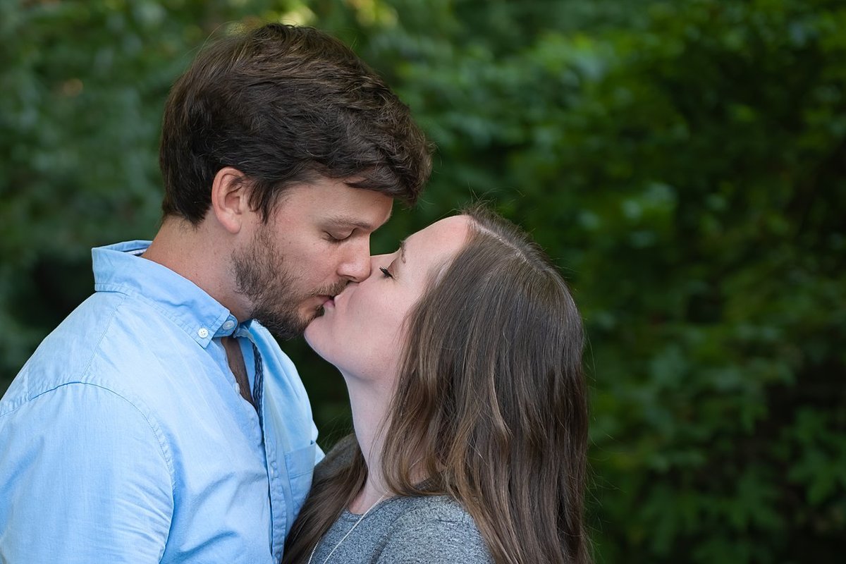 Engaged couple kissing during their engagement session in a wooded area of Pittsburgh, PA