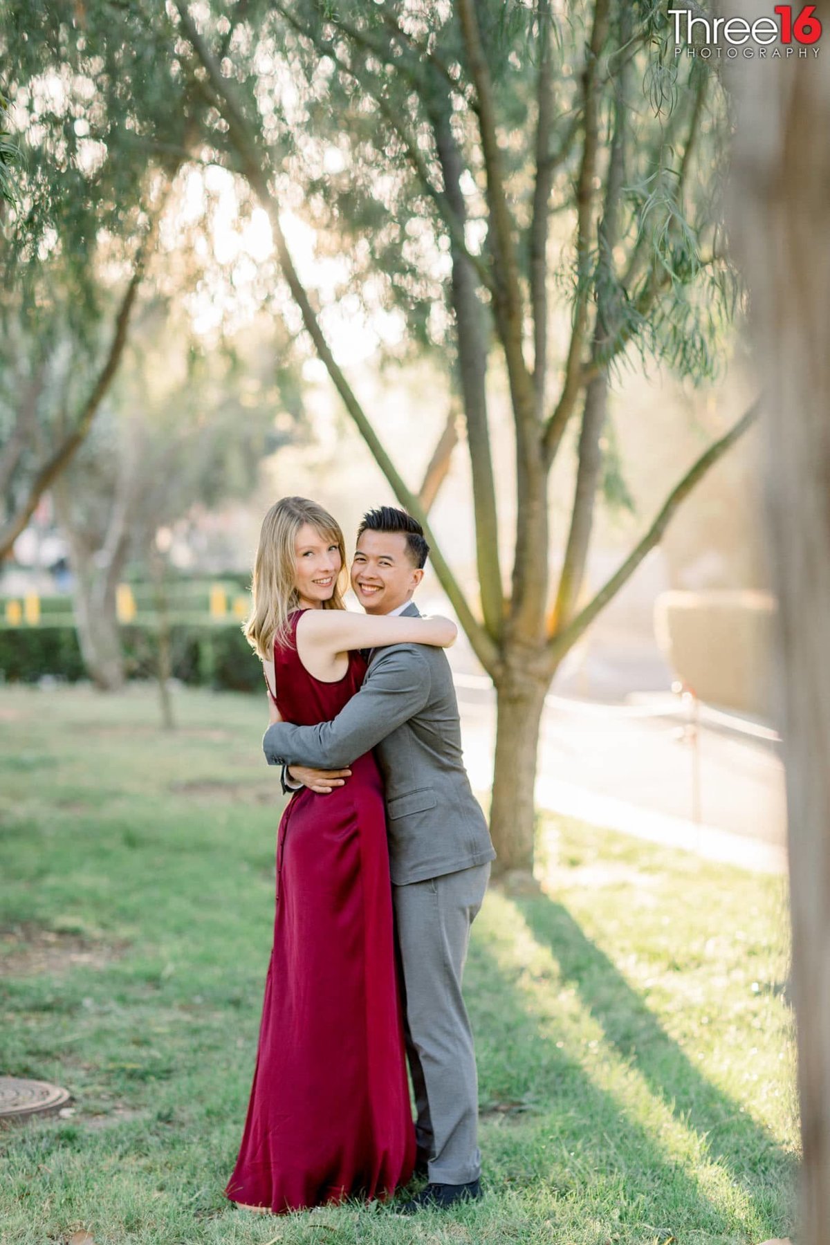 Engaged couple pose for photos as they embrace
