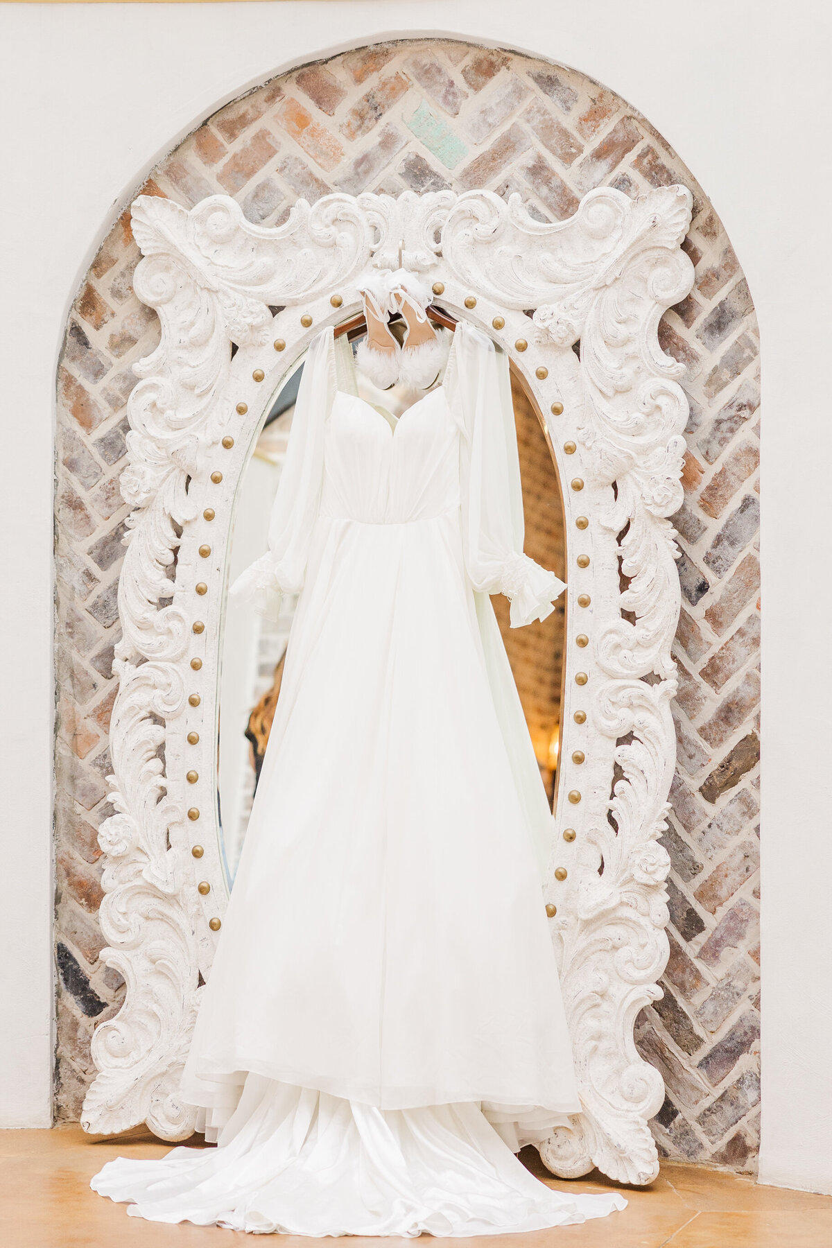 ivory-boho-wedding-dress-hanging-on-an-ornate-white-mirror