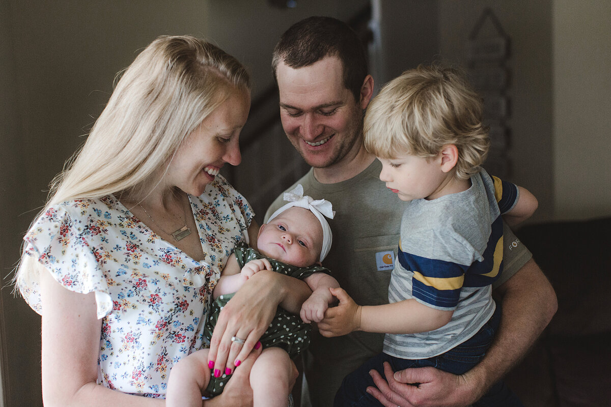 Mom and dad holding bay and toddler in newborn pictures by Nicola Herring