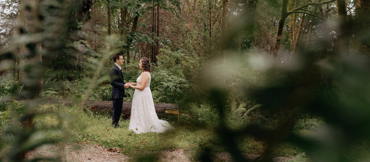 Bride and groom holding hands during an intimate forest wedding ceremony.