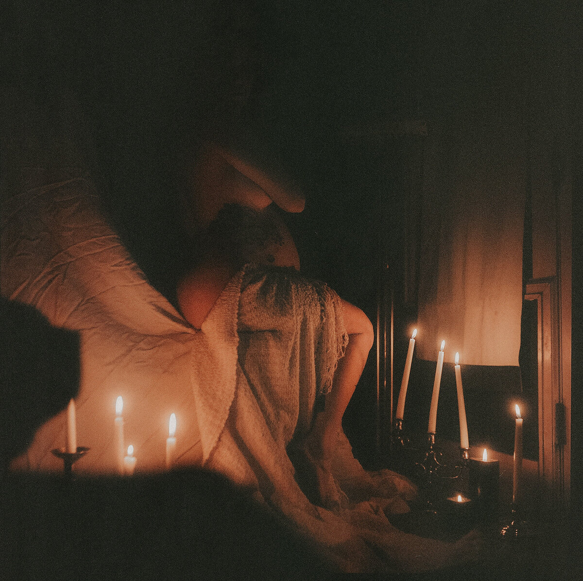 Pregnant woman lying in a bed with her pregnant belly exposes in low light.