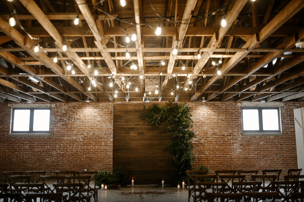 Romantic industrial wedding reception with greenery and fairy lights