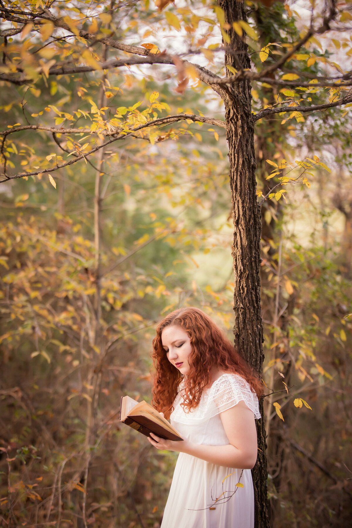senior reading a book in fall leaves