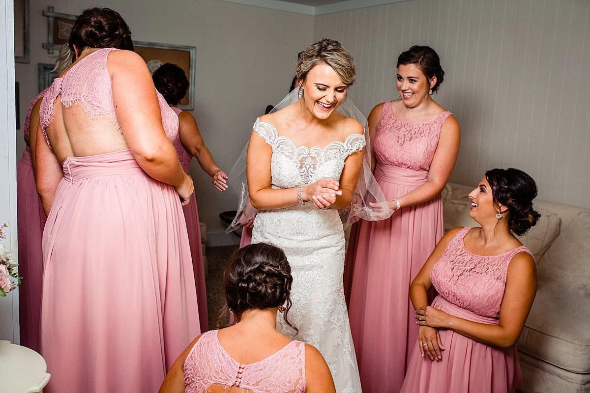 Bride putting on perfume  laughing while chatting with bridesmaids