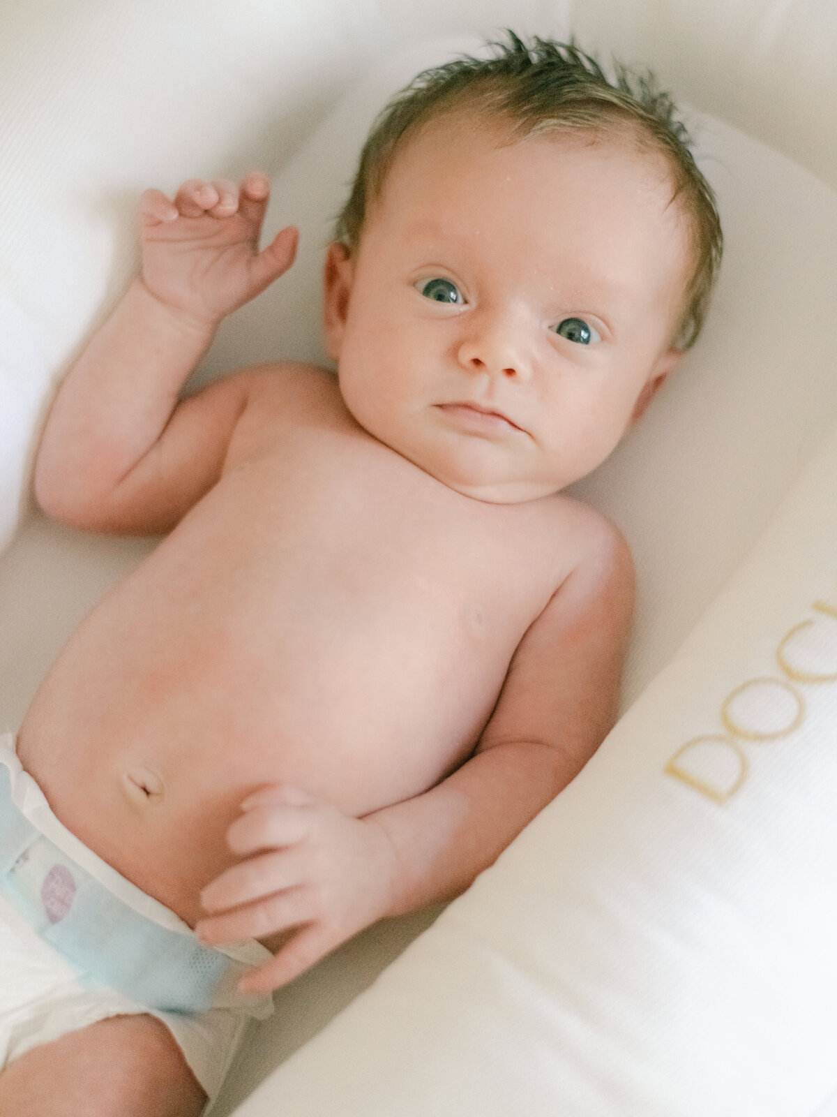 Baby in diaper while laying in her crib.