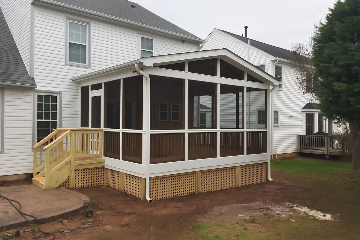 Screened porch addition on two-story white home with wood steps and railing.
