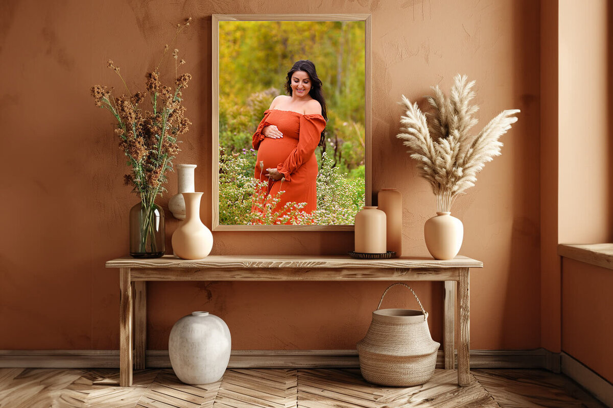 boho-style room with a framed photo of a woman wearing an orange dress for her fall maternity photography session in Burlington, Ontario