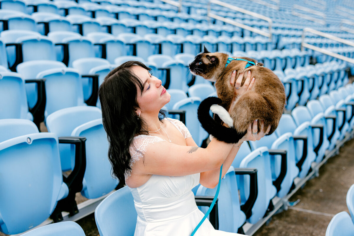 Graduation session with graduate's cat at campus football stadium.