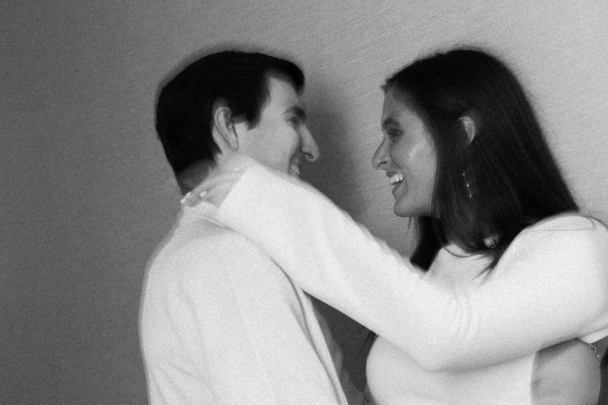 A timeless black and white engagement portrait of Rebecca and Graysen laughing together in an intimate hallway moment at Marriott Hotel Fort Lauderdale, captured by Claudia Amalia Photography.