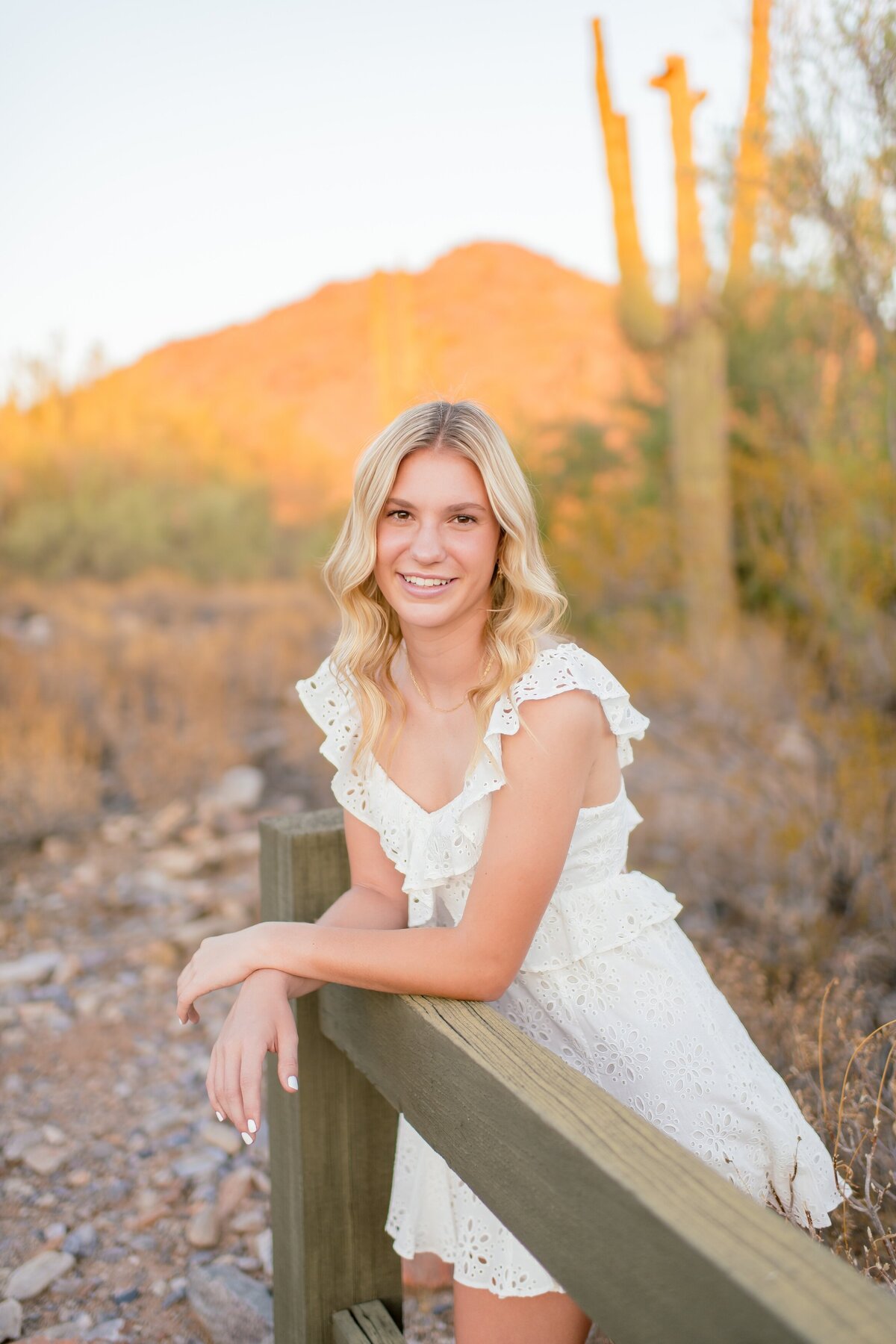 senior girl standing in the desert in a white dress