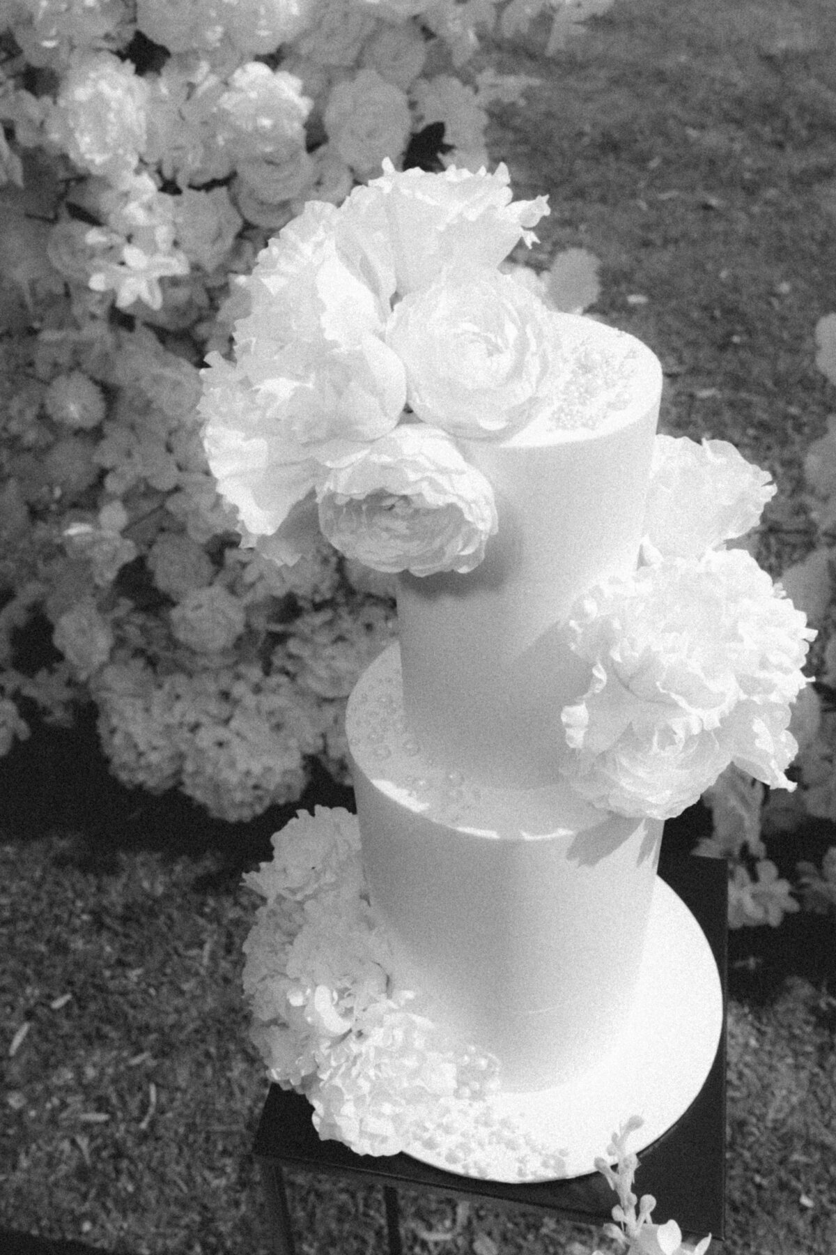 Zwart-witfoto van bruidstaart met bloemen