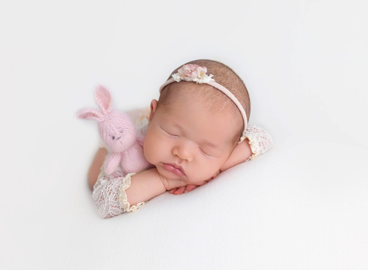 Newborn baby girl in pink holding tiny pink bunny in Brooklyn NYC studio