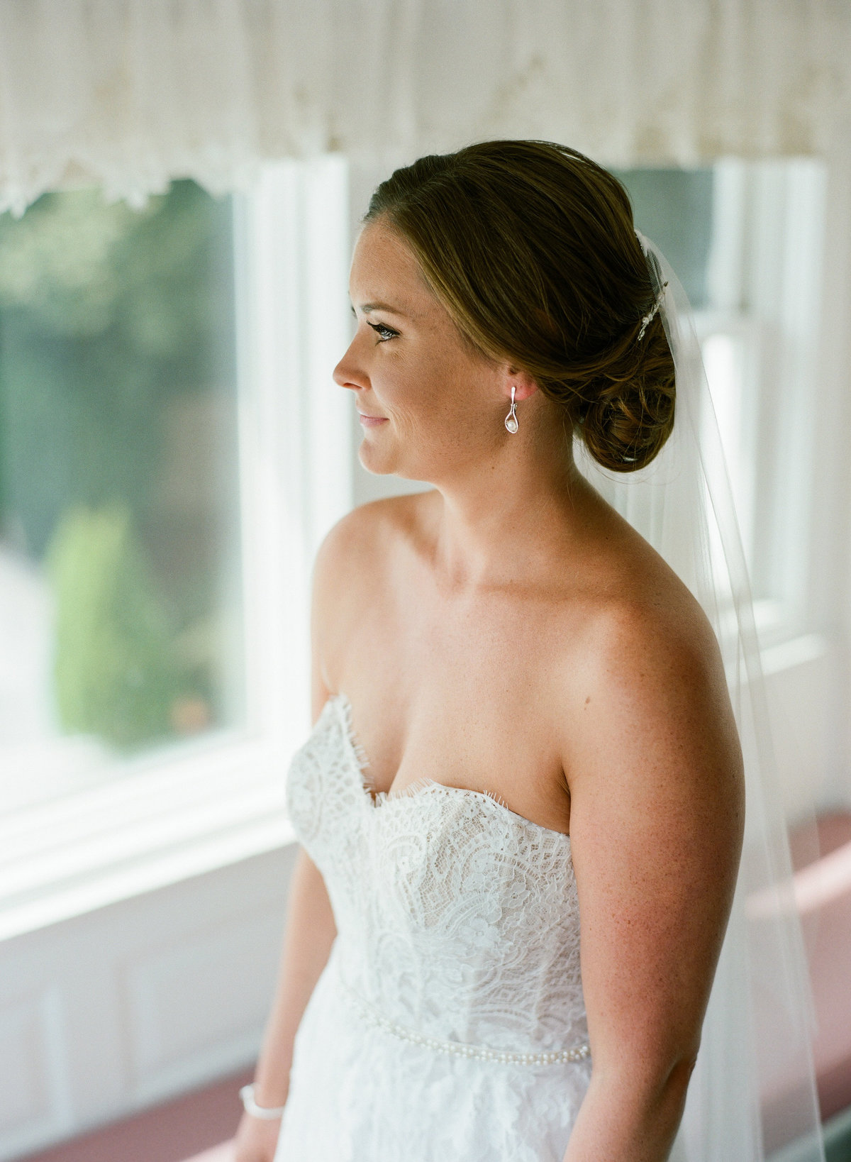 Bride looks out window on wedding day