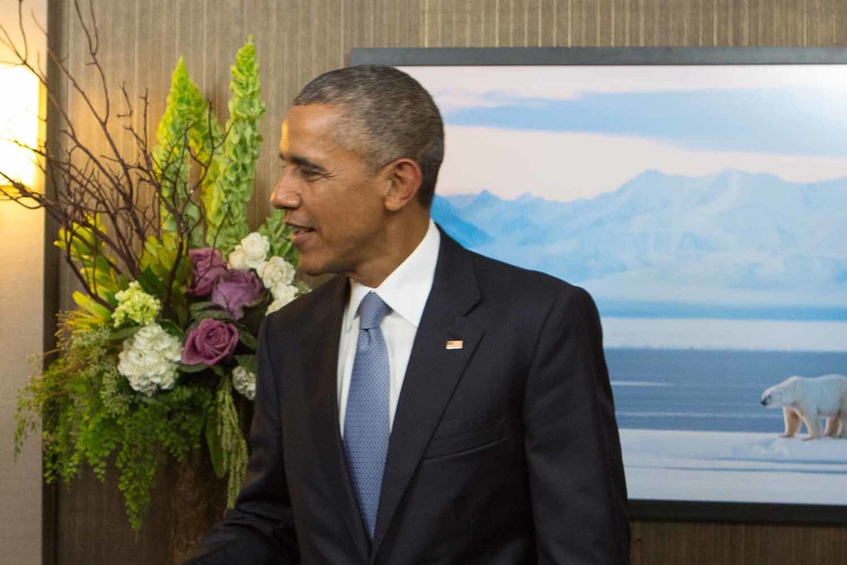 President Obama with tall flower arrangement of bells of ireland, purple roses, white roses, manzanita branches, and green amaranthus