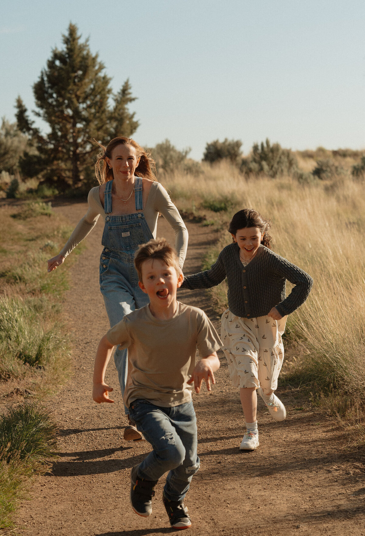 candid photo of mother and two children running together through the scenic trails at Smith Rock