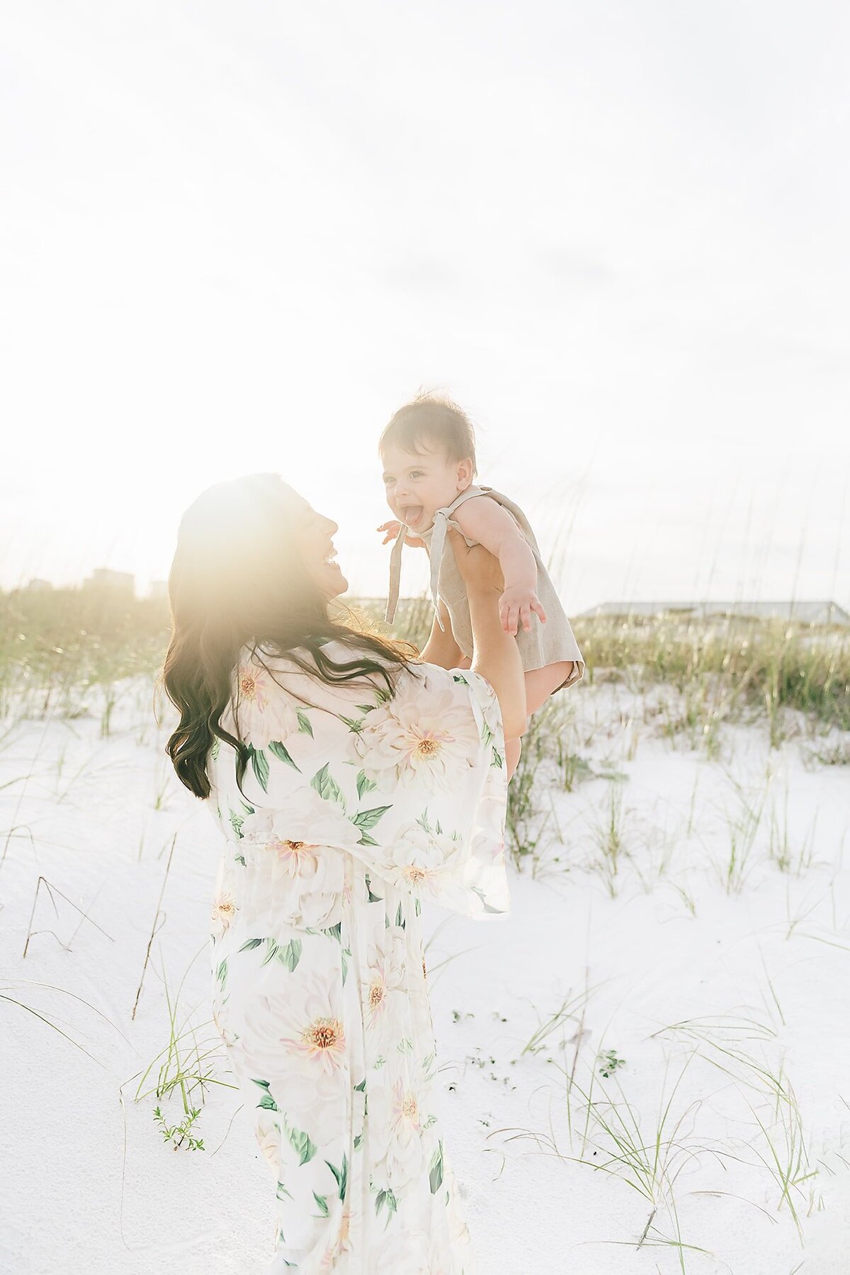 A mother making her baby smile at the beach