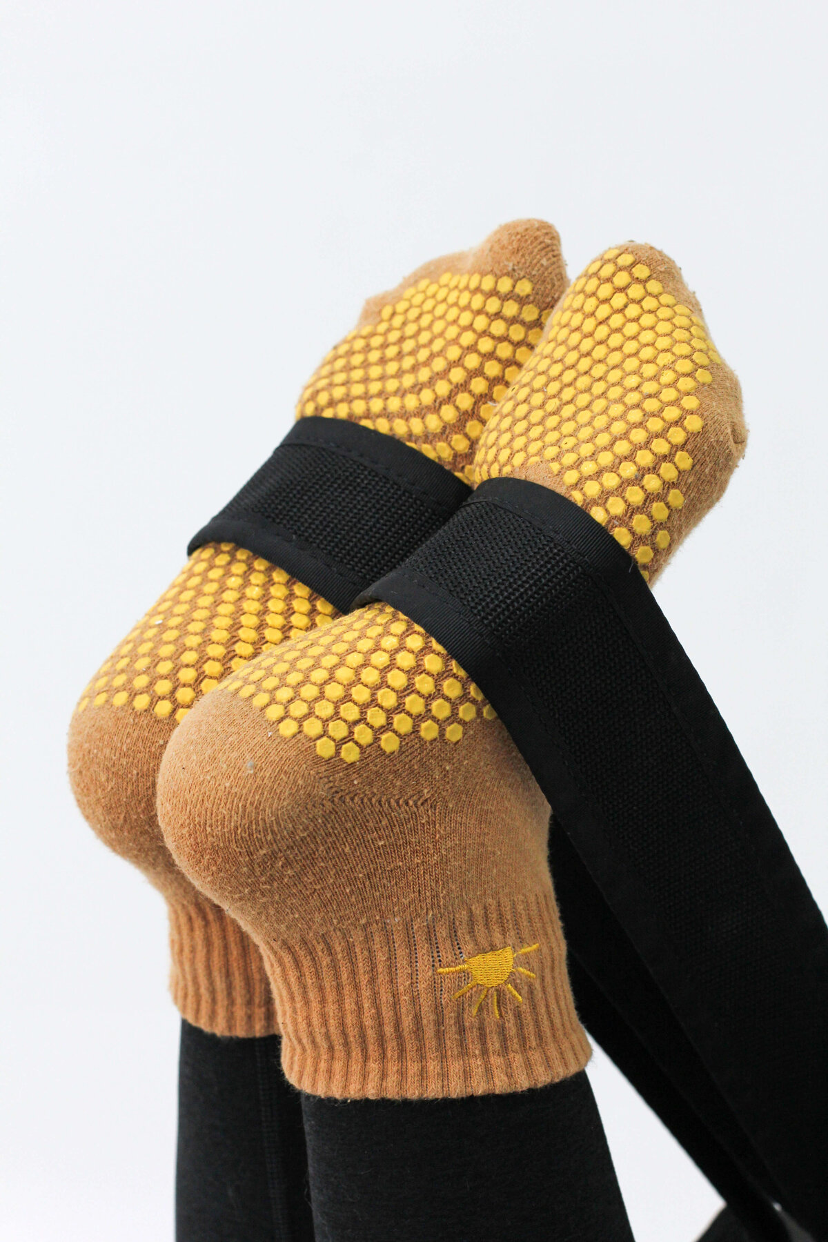 Detailed view of foot placement in black Megaformer strap using yellow grip socks at Rise Lagree Studio