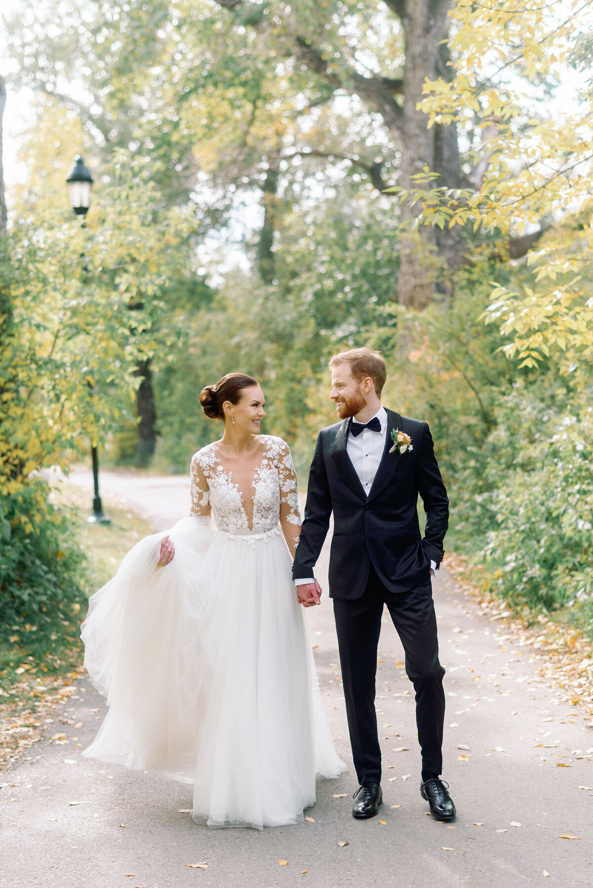Gorgeous bride and groom walking together at sunset, captured by Kaity Body Photography, elegant film inspired wedding photographer in Calgary, Alberta. Featured on the Bronte Bride Vendor Guide.