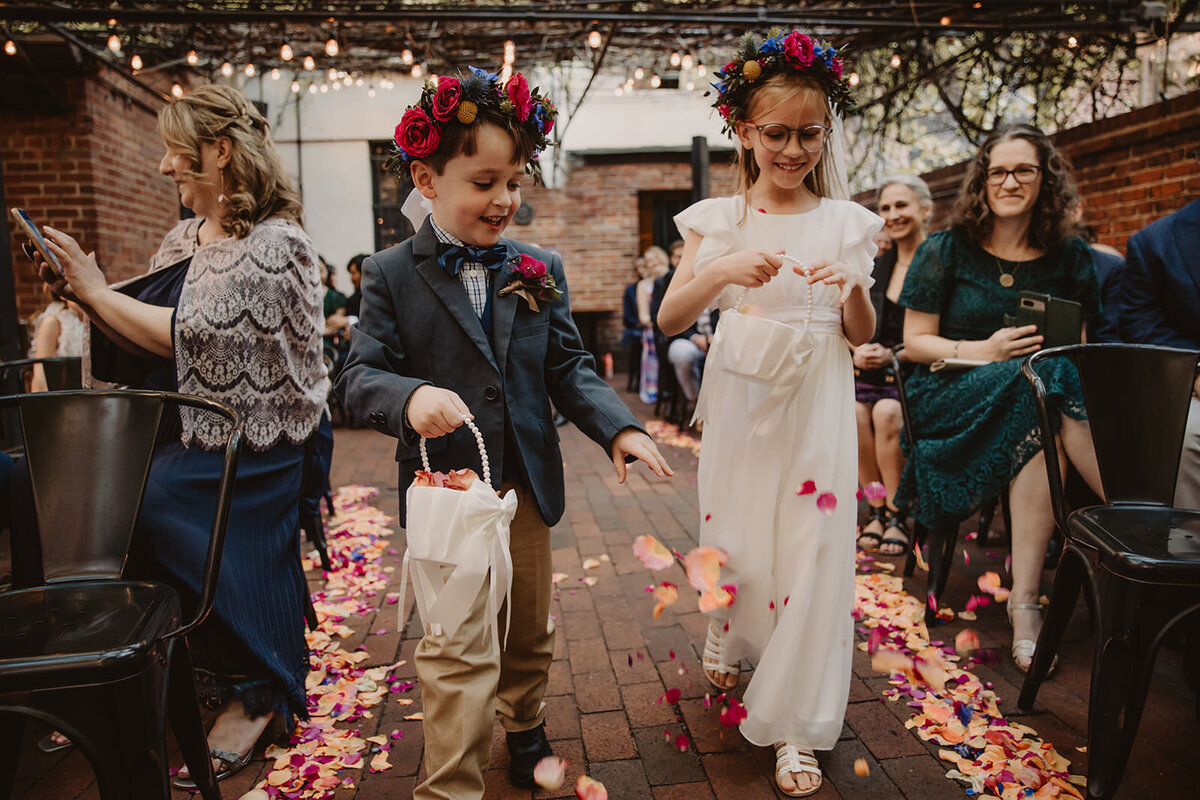 Two small kids dropping flower petals on the aisle at a wedding 