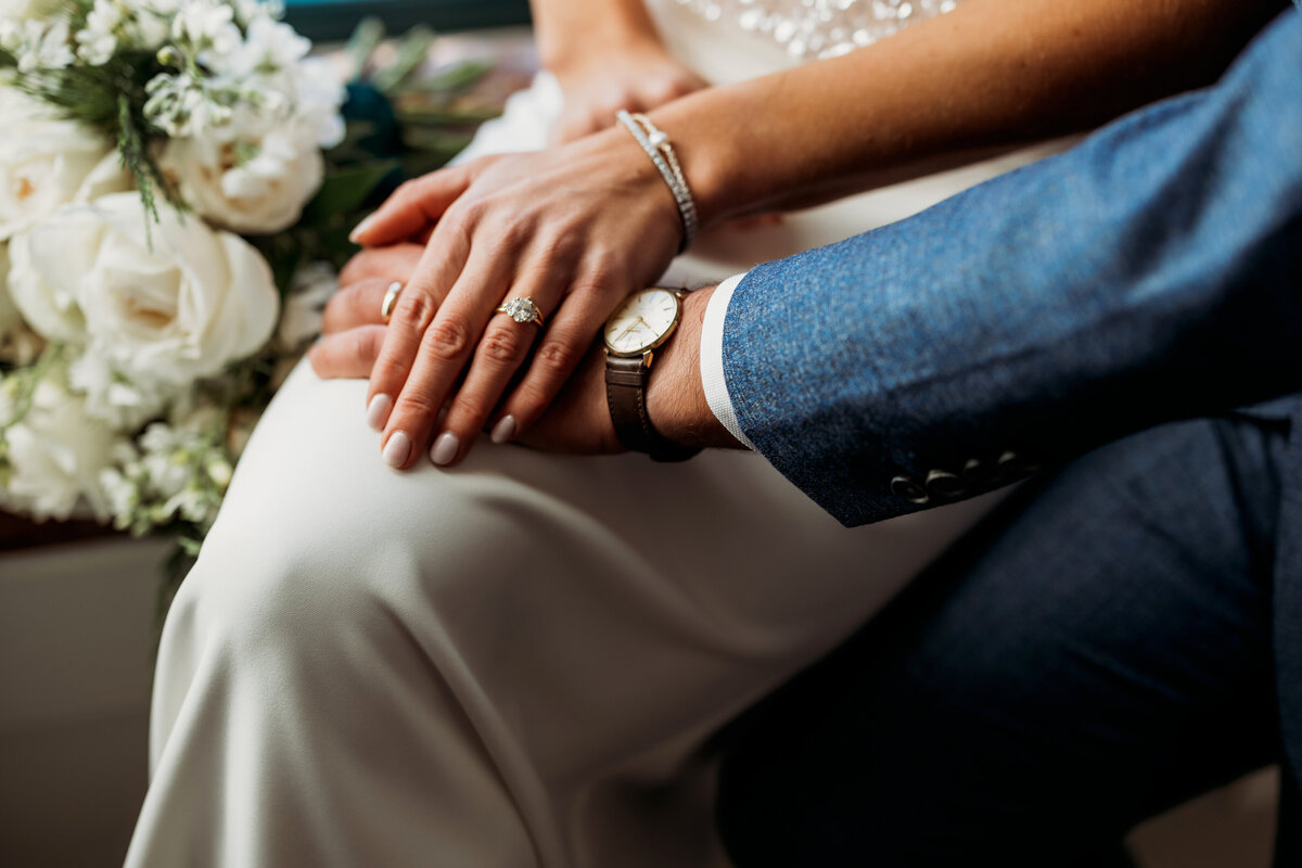 Husband and wife stack their hands to show off their watch and jewelry 