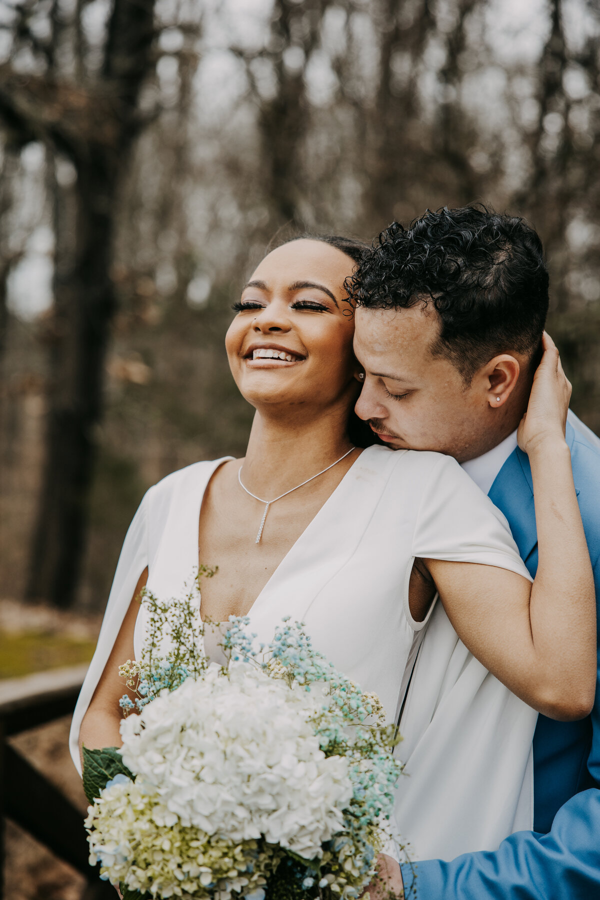 Bridal portraits at Kincaid Manor featuring a joyful bride holding the groom’s face while laughing, as he kisses her neck.
