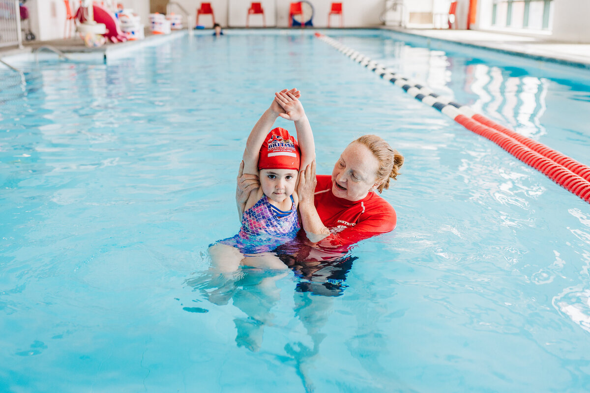 swim instructor shows girl how to dive in pool