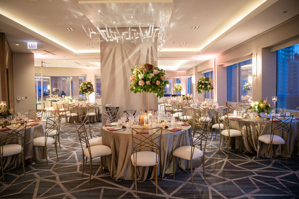 A large room with tables and chairs set up for a wedding reception
