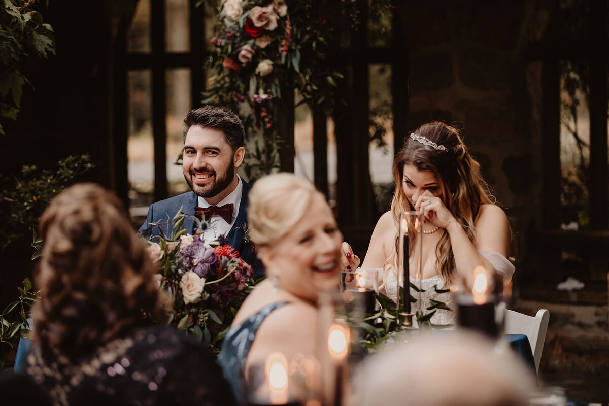 a wedding couple laughing at their reception 