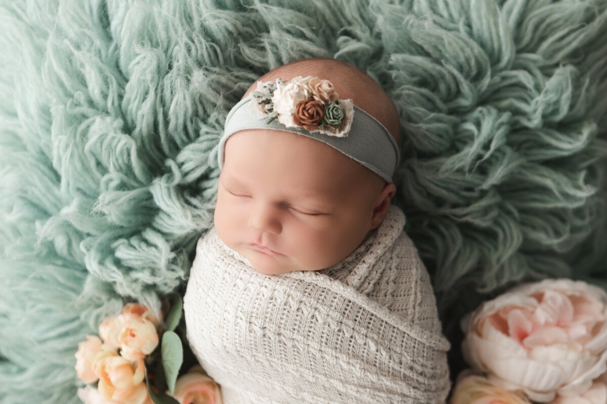 newborn in white wrap with green floral headband