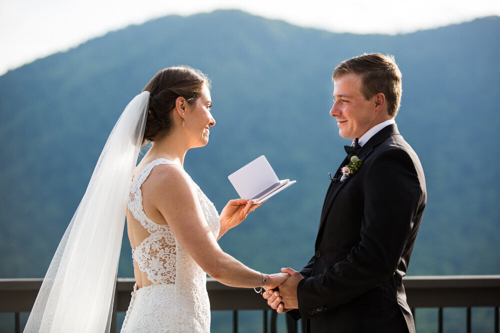 bride says her vows to the groom with a mountain vista behind them