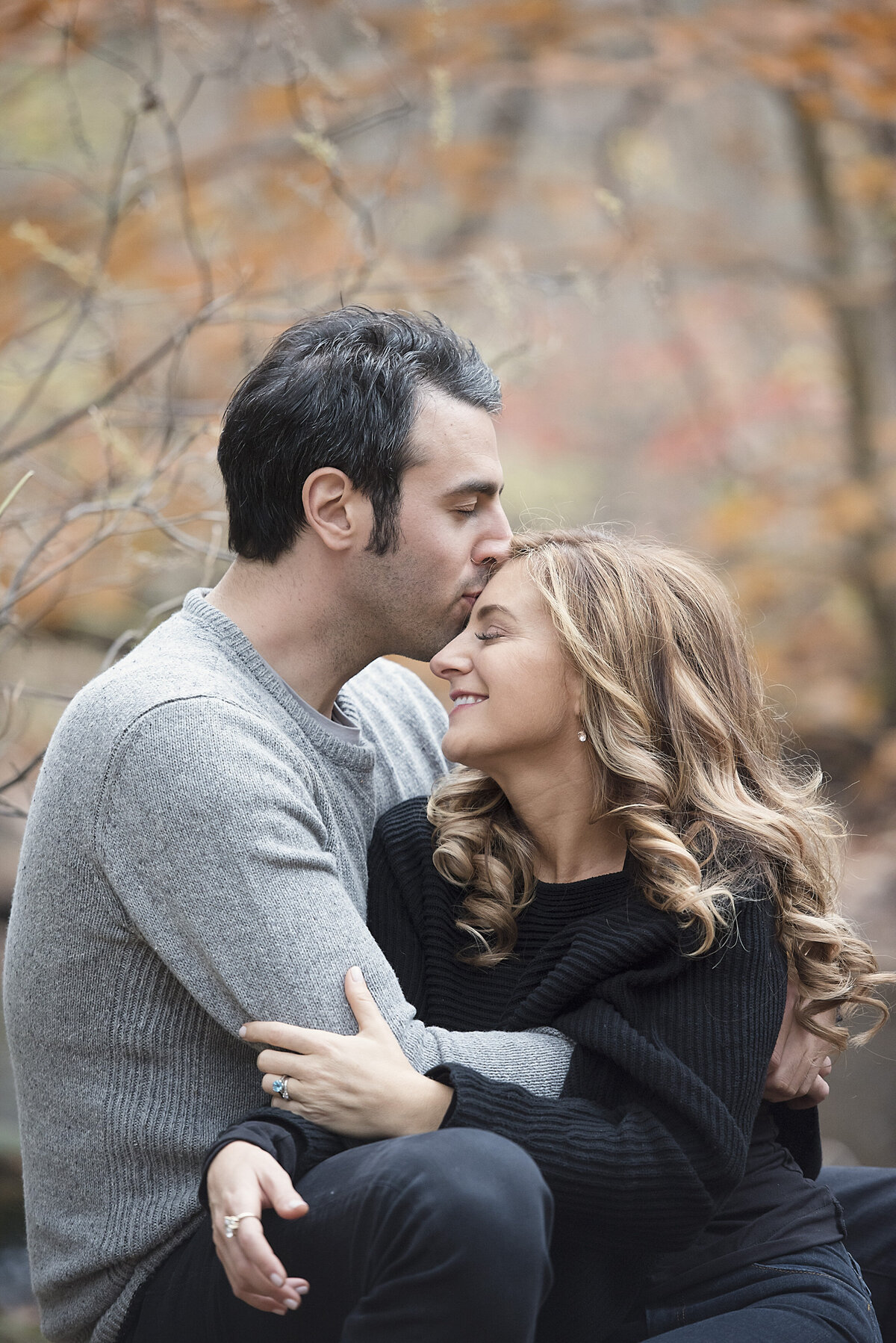 A person kissing their partner's head as they sit together
